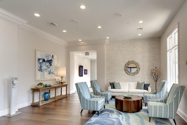 living area with ornamental molding, wood finished floors, and visible vents