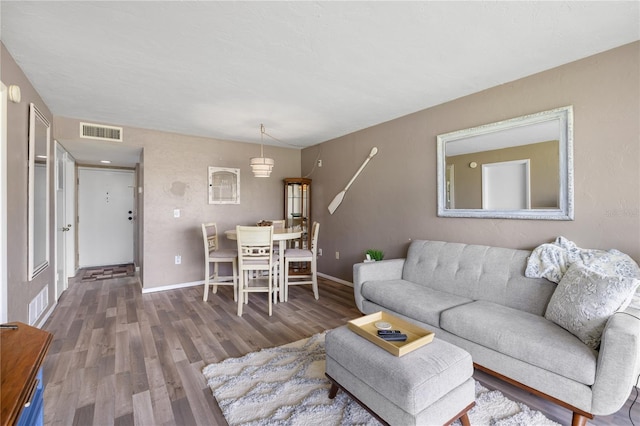 living room featuring wood finished floors, visible vents, and baseboards