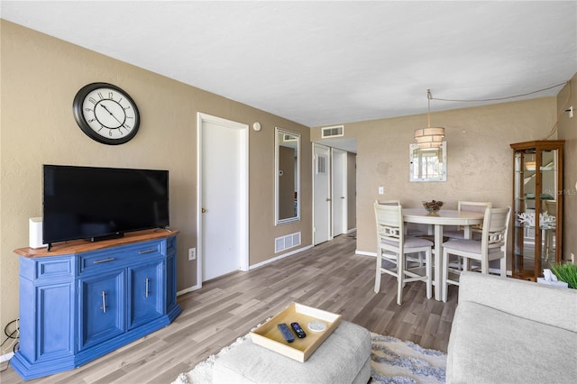 living area with visible vents, light wood-type flooring, and baseboards