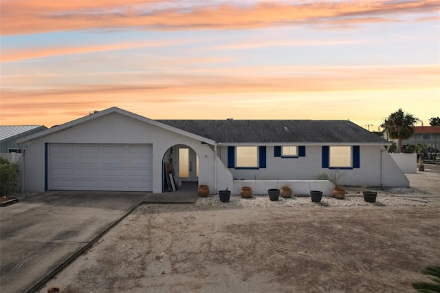 ranch-style house featuring concrete driveway, an attached garage, and stucco siding