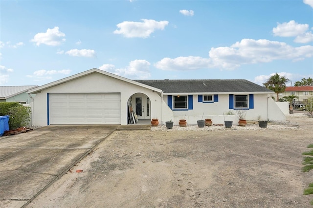 ranch-style house featuring concrete driveway, an attached garage, and stucco siding