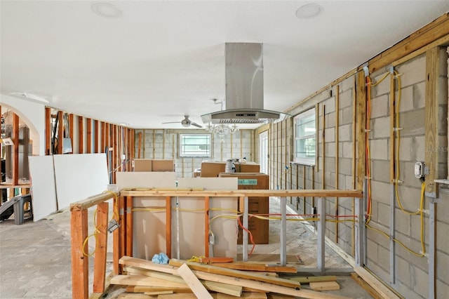 misc room featuring concrete block wall, ceiling fan, and unfinished concrete flooring