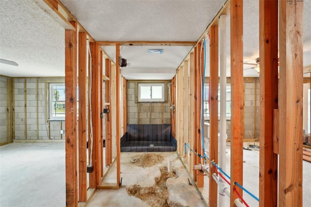 miscellaneous room with concrete block wall, ceiling fan, and a textured ceiling