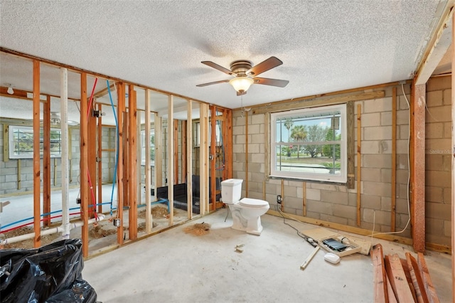 miscellaneous room featuring ceiling fan, a textured ceiling, and concrete block wall