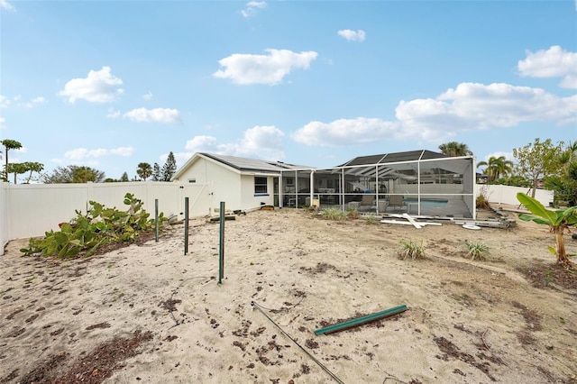 rear view of house featuring a lanai, a fenced backyard, and a swimming pool