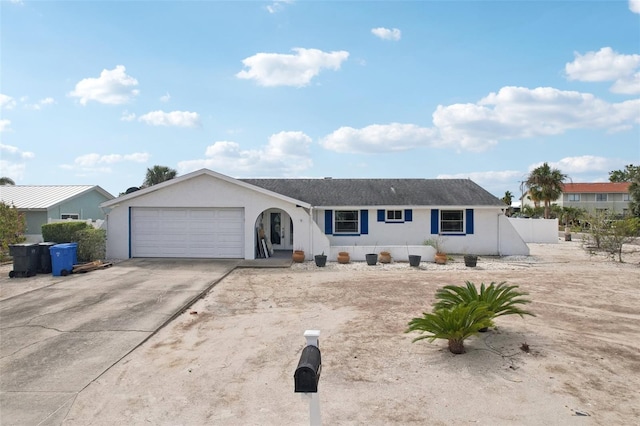 ranch-style home with driveway, an attached garage, fence, and stucco siding