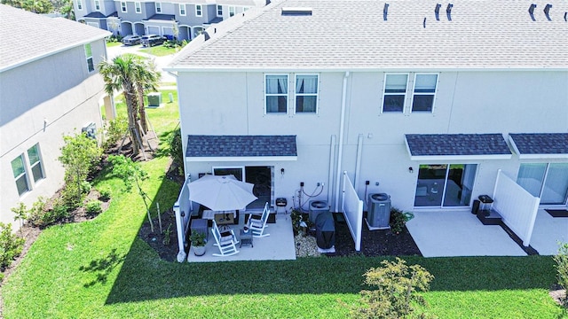 back of property with central AC, a shingled roof, a lawn, and a patio area