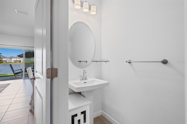 bathroom with visible vents, a water view, baseboards, and tile patterned floors