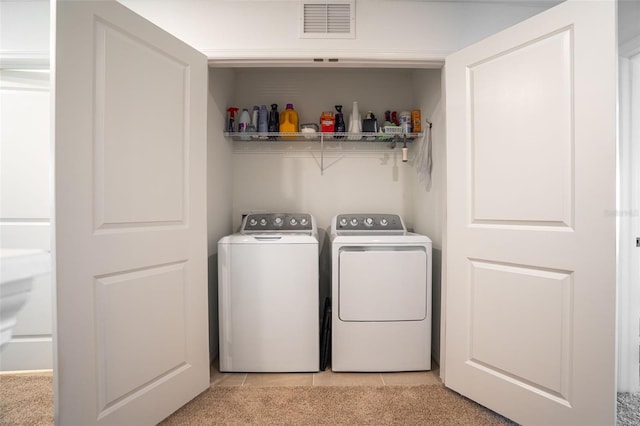 washroom featuring light tile patterned floors, light colored carpet, laundry area, separate washer and dryer, and visible vents