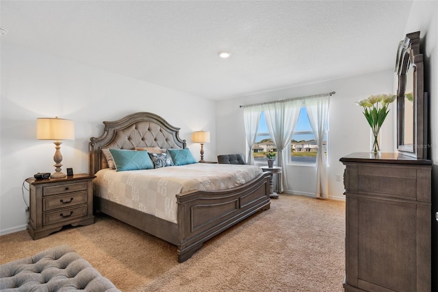 bedroom featuring light colored carpet, a textured ceiling, and baseboards