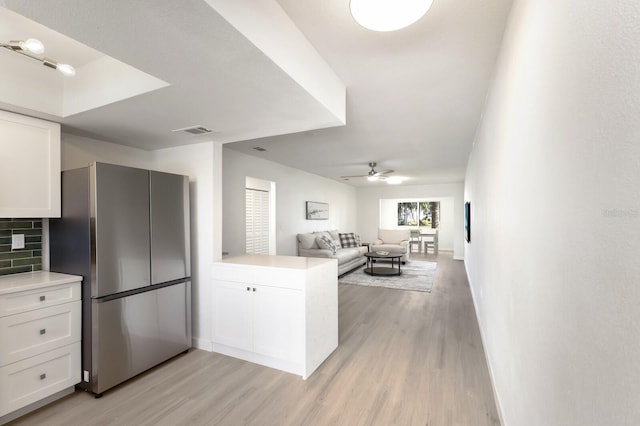 kitchen featuring freestanding refrigerator, visible vents, a peninsula, and white cabinetry