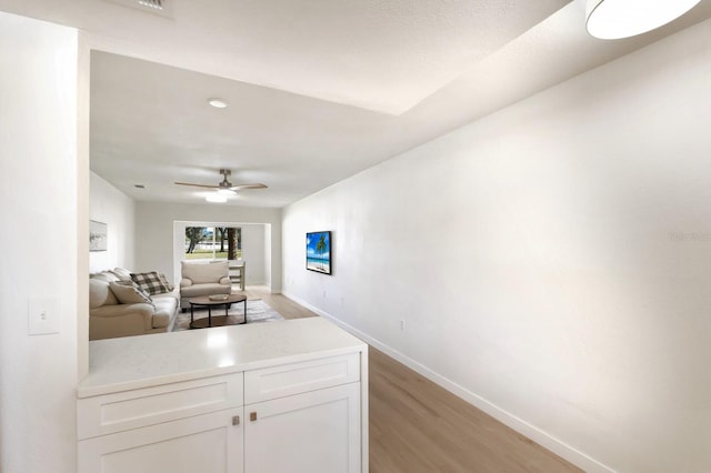 kitchen featuring baseboards, white cabinets, a ceiling fan, light countertops, and light wood-style floors