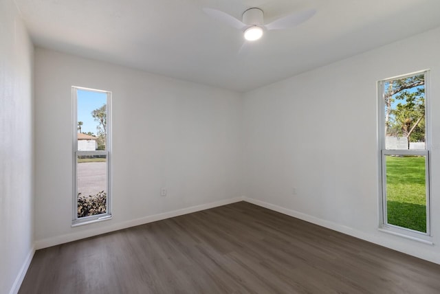 empty room with plenty of natural light, baseboards, ceiling fan, and dark wood-type flooring