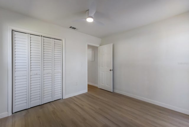 unfurnished bedroom with ceiling fan, wood finished floors, visible vents, baseboards, and a closet