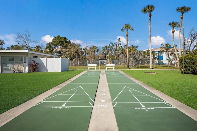 view of community featuring shuffleboard, fence, and a yard