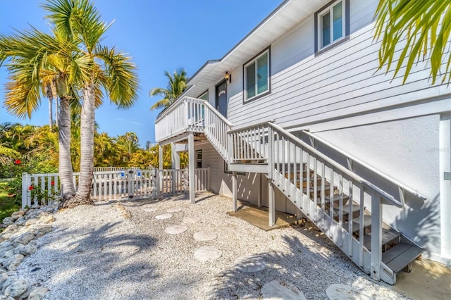 view of property exterior with a deck, stairway, and fence