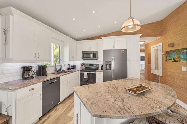 kitchen with appliances with stainless steel finishes, vaulted ceiling, white cabinetry, and a sink