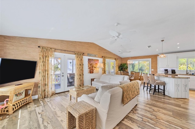 living area featuring french doors, lofted ceiling, visible vents, a ceiling fan, and light wood-type flooring