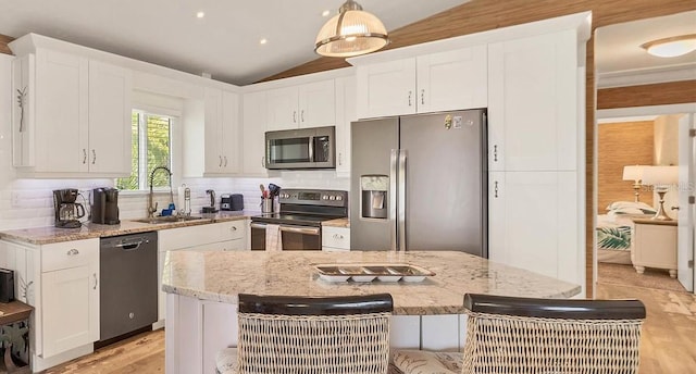 kitchen featuring tasteful backsplash, lofted ceiling, stainless steel appliances, white cabinetry, and a sink