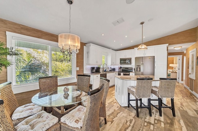 dining space with lofted ceiling, light wood finished floors, visible vents, and a chandelier