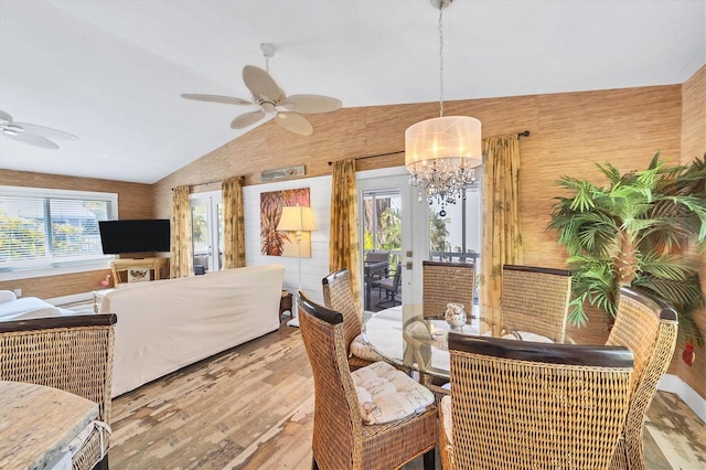 dining room with vaulted ceiling, ceiling fan with notable chandelier, and wood finished floors