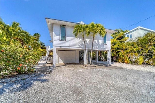 coastal home with a garage, stairs, a carport, and gravel driveway