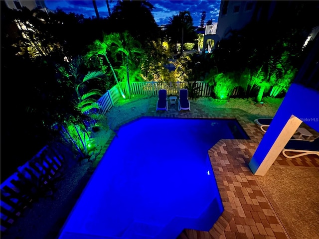 pool at twilight featuring a patio area and a fenced backyard