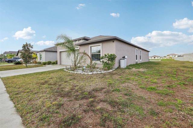 view of side of property featuring driveway, an attached garage, a lawn, and stucco siding