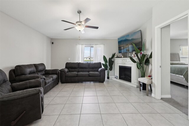 living room with light tile patterned floors, ceiling fan, a fireplace, and a healthy amount of sunlight