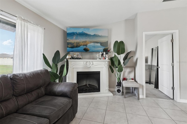 living area featuring light tile patterned floors, baseboards, and a fireplace with raised hearth