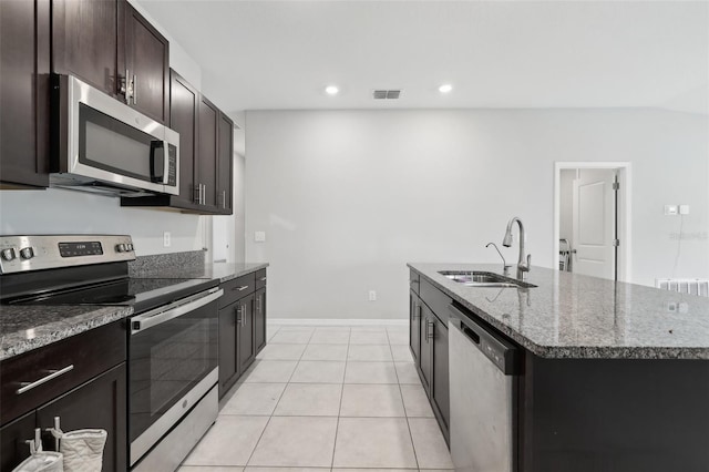 kitchen with a center island with sink, visible vents, appliances with stainless steel finishes, dark stone countertops, and a sink