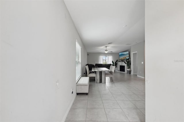 living area with a ceiling fan, light tile patterned flooring, and baseboards