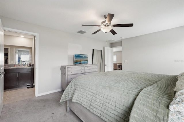 bedroom featuring light carpet, a ceiling fan, visible vents, baseboards, and ensuite bath