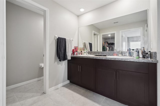 bathroom with tile patterned flooring, baseboards, a spacious closet, and vanity