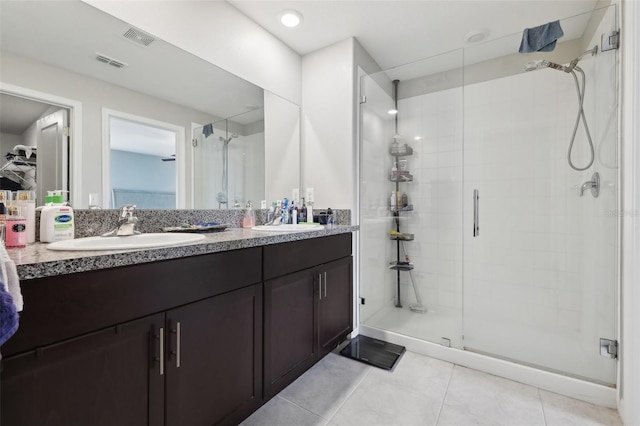 bathroom with double vanity, a shower stall, visible vents, and a sink