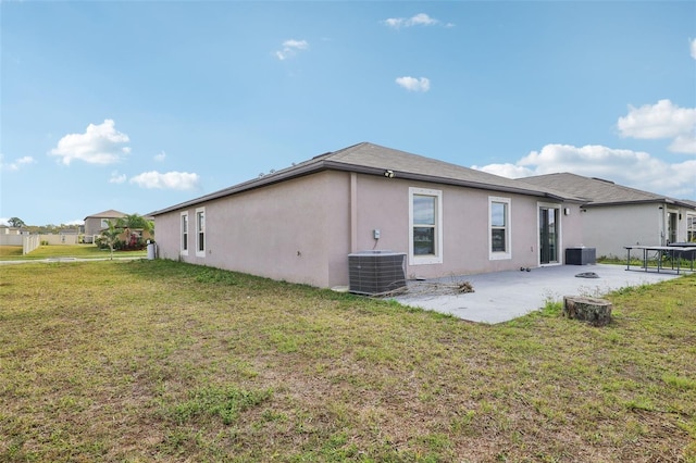 rear view of house with a yard, central air condition unit, a patio, and stucco siding