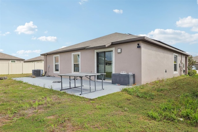 rear view of house with stucco siding, a patio area, a lawn, and fence