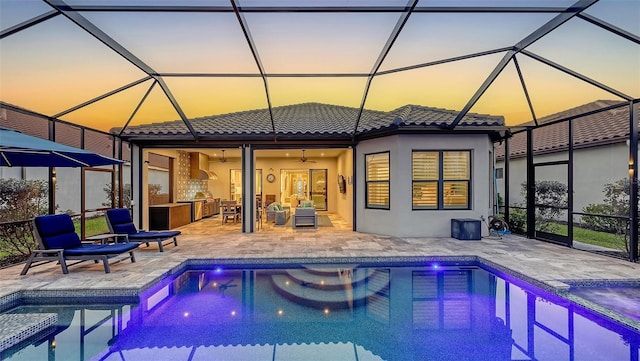 pool at dusk with an outdoor pool, ceiling fan, an outdoor hangout area, and a patio