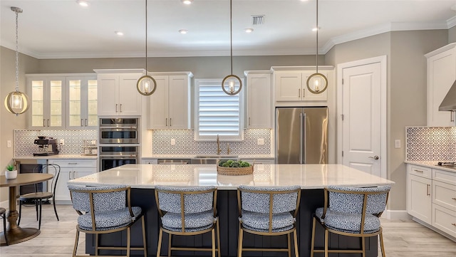 kitchen featuring light wood-style flooring, a sink, a center island, white cabinetry, and appliances with stainless steel finishes