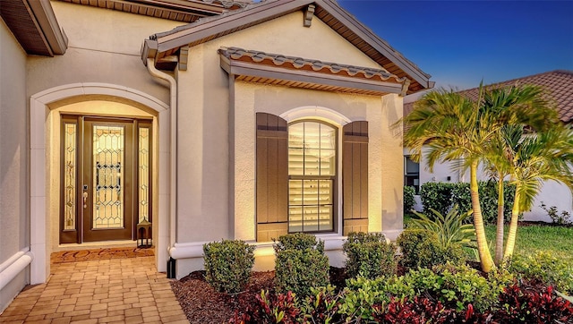 property entrance featuring a tiled roof and stucco siding