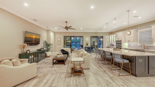 living room with light wood finished floors, visible vents, and ornamental molding