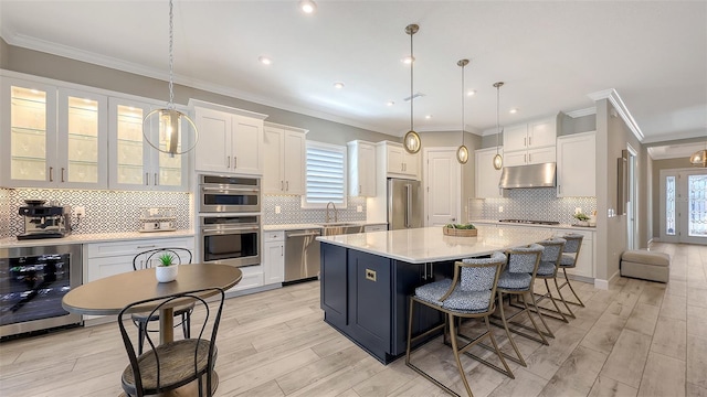 kitchen with stainless steel appliances, light countertops, wine cooler, under cabinet range hood, and white cabinetry