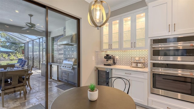 dining area featuring stone tile flooring, a ceiling fan, beverage cooler, and crown molding