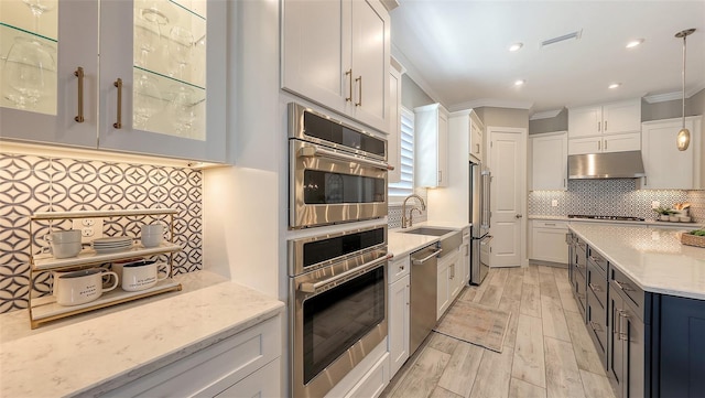 kitchen with visible vents, a sink, stainless steel appliances, under cabinet range hood, and backsplash