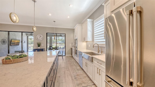 kitchen with backsplash, appliances with stainless steel finishes, crown molding, and a sink