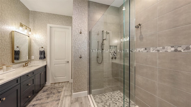 bathroom with double vanity, a shower stall, wood finished floors, and a sink