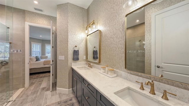 ensuite bathroom featuring a tile shower, visible vents, ensuite bath, and a sink