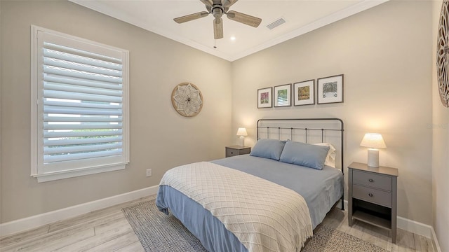 bedroom featuring a ceiling fan, wood finished floors, baseboards, visible vents, and crown molding