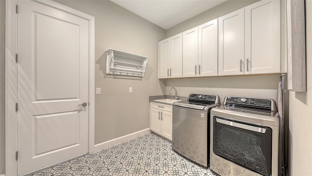 washroom featuring a sink, cabinet space, baseboards, and separate washer and dryer