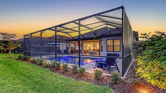 rear view of house with a yard, glass enclosure, a patio area, an outdoor pool, and a tiled roof